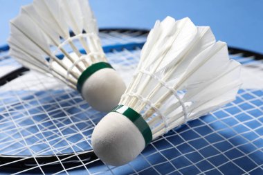 Tüylü badminton mekikleri ve raketleri mavi arka planda yakın plan
