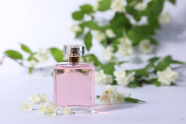 Şişede Aromatik parfüm ve beyaz arka planda güzel yasemin çiçekleri.