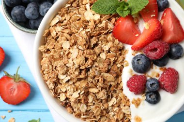 Böğürtlenli tahıl gevreği ve açık mavi ahşap masada yoğurt.