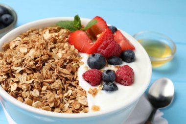 Böğürtlenli ve yoğurtlu leziz granola açık mavi masada, yakın plan.