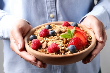 Elinde böğürtlenli, fındıklı ve nane arkaplanlı lezzetli granola taşıyan kadın, yakın plan.