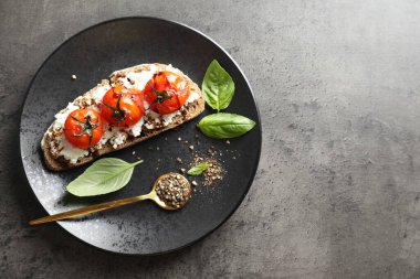 Lezzetli ricotta bruschetta, güneşte kurutulmuş domates, sos, fesleğen ve öğütülmüş biber, gri desenli masa, üst manzara. Metin için boşluk
