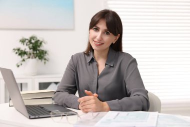 Portrait of smiling secretary at table in office