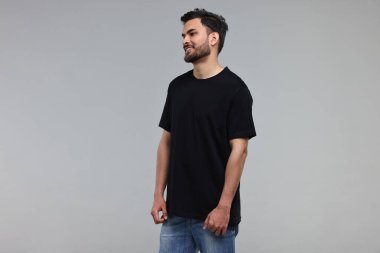 Gri arka planda siyah tişörtlü gülen adam.
