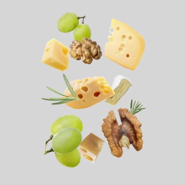 Açık gri arka planda farklı peynir, kraker, üzüm, biberiye ve ceviz çeşitleri