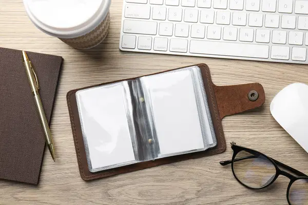 Stock image Leather business card holder with blank cards, stationery and keyboard on wooden table, flat lay