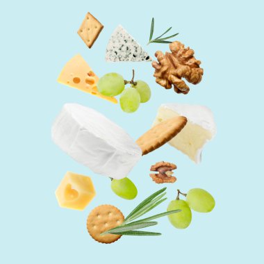 Açık mavi arka planda farklı peynir, kraker, üzüm, biberiye ve ceviz çeşitleri