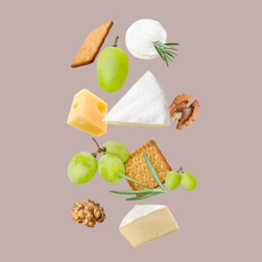 Gri arka planda farklı peynir, kraker, üzüm, biberiye ve ceviz çeşitleri