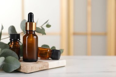 Aromaterapi. Gerekli yağ ve okaliptüs şişeleri beyaz mermer masa üzerinde yapraklar, metin için boşluk