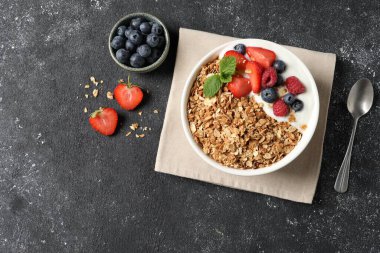 Koyu dokulu masada servis edilen böğürtlenli ve yoğurtlu lezzetli granola. Metin için boşluk