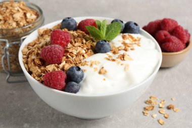 Gri desenli masada meyveli granola ve yoğurt, yakın plan.