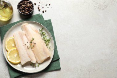 Çiğ morina balığı, baharat, mikro yeşillik ve limon tabağı, gri desenli masa, düz yatak. Metin için boşluk