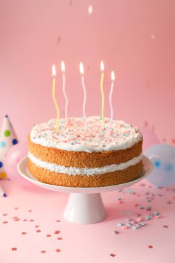 Tasty cake with colorful candles on pink background