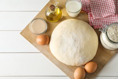 Çiğ hamur ve malzemeler beyaz ahşap masa üzerinde, üst manzara. Metin için boşluk