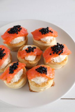 Krem peynirli lezzetli puf böreği, somon balığı ve beyaz ahşap masada siyah havyar.