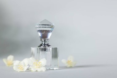 Şişede Aromatik parfüm ve gri arka planda güzel yasemin çiçekleri, metin için boşluk