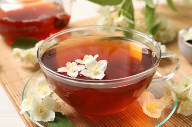 Sıcak yasemin çayı fincanda ve çiçekler beyaz ahşap masada, yakın plan