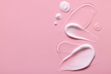 Pembe arka planda yüz kremi örnekleri, üst manzara. Metin için boşluk
