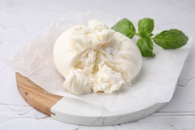 Beyaz desenli masada fesleğen yapraklı lezzetli taze burrata peyniri.