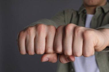 Gri arkaplanda dövmesi için yer olan yumrukları gösteren adam, yakın plan