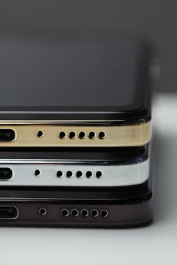 Stack of modern smartphones on white table, closeup