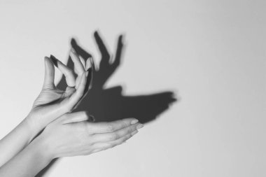 Gölge kuklası. Kadın, hafif arka planda geyik gibi el hareketi yapıyor, mesaj için yere yakın çekim yapıyor. Siyah ve beyaz etkisi