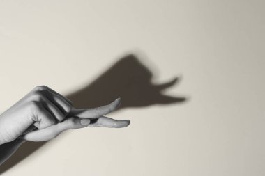 Gölge kuklası. Kadın, arka planda salyangoz gibi el hareketi yapıyor, mesaj için yeri olan bir yere yakın çekim yapıyor. Siyah ve beyaz etkisi
