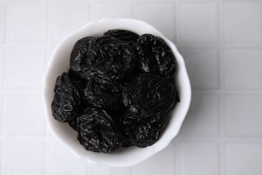 Lezzetli kuru erikler (kuru erik) beyaz döşeme üzerinde kasede, üst manzara