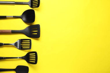 Sarı arka planda farklı spatulalar, düz yatış. Metin için boşluk