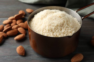 Kepçe içinde taze badem unu ve ahşap masada fındıklar, yakın plan.