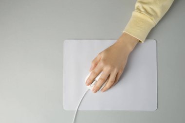 Gri arka planda modern bilgisayar faresi kullanan bir kadın. Metin için boşluk