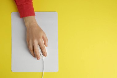 Sarı arka planda modern bilgisayar faresi kullanan bir kadın. Metin için boşluk