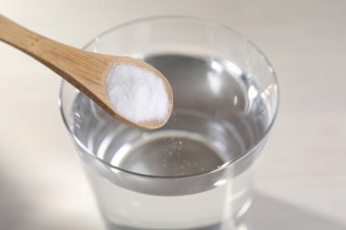 Işık arkaplanındaki su bardağına kabartma tozu eklemek, yakın plan