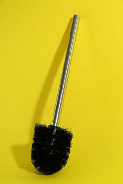 Sarı arka planda bir tuvalet fırçası. Temizlik aracı