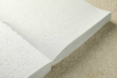 Bej desenli masa üzerine Braille metni olan kitap, yakın plan. Körler için eğitim ve eğlence