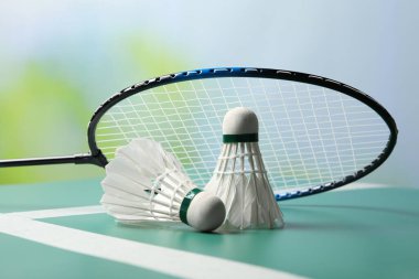 Tüylü badminton mekik penisleri ve raket yeşil masada bulanık arka plan, yakın plan