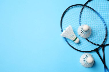Tüy badminton mekikleri ve raketler açık mavi arka planda, düz yatıyordu. Metin için boşluk