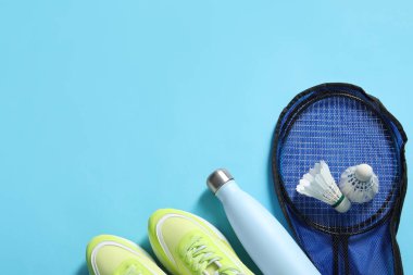 Badminton seti, spor ayakkabıları ve açık mavi arka planda şişe, düz yatış. Metin için boşluk