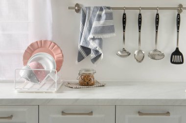 Mutfaktaki beyaz masada farklı temiz bulaşık takımları olan bir Drainer.