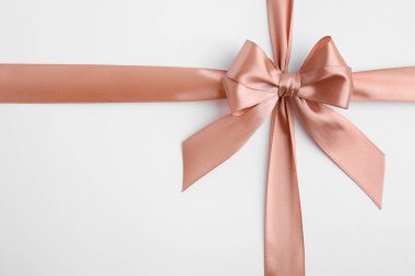 Beyaz arka planda fiyonklu bej saten kurdele, üst görünüm