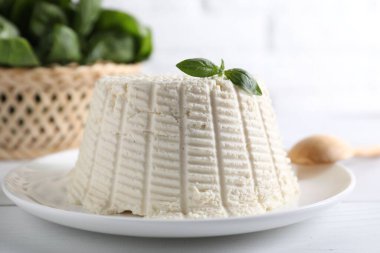 Beyaz masada fesleğenli taze ricotta (krem peynir), yakın plan.