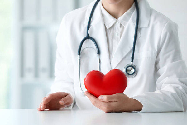 Врач с красным сердцем за столом в клинике, крупный план