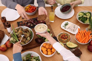 Ahşap masada vejetaryen yemekleri yiyen arkadaşlar, yakın plan.