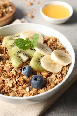 Gri masada taze meyveli lezzetli granola, yakın plan.