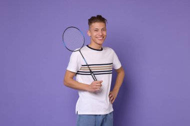 Mor arka planda badminton raketi olan genç bir adam.