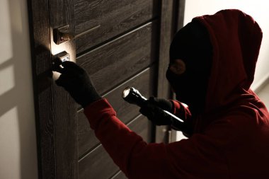 El fenerli bir hırsız holdeki yabancı kapının kilidini kırıyor. Hırsızlık.