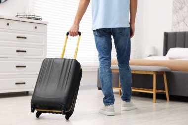 Bavullu bir misafir otel odasında yürüyor, yakın plan.