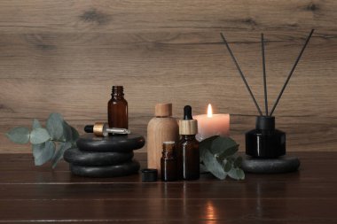 Aromaterapi ürünleri ve ahşap masada yanan mum.