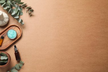 Kahverengi arka planda farklı aromaterapi ürünleri ve okaliptüs yaprakları var. Metin için boşluk