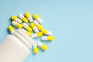 Açık mavi arka planda antibiyotik haplar ve şişe, üst manzara. Metin için boşluk